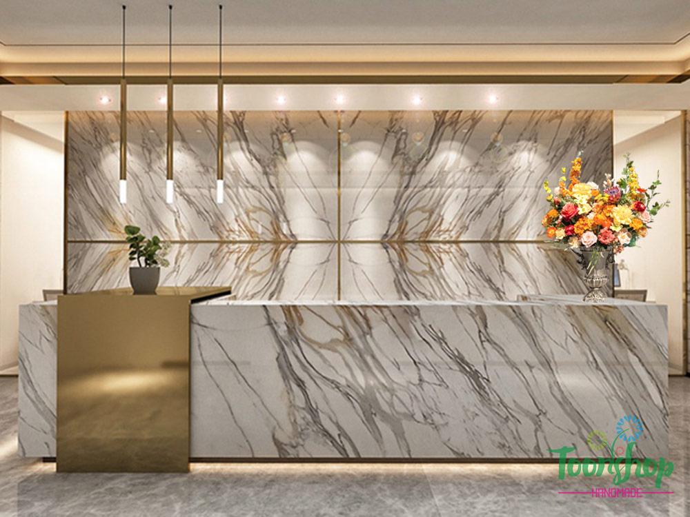 Bình hoa lụa màu cam đặt tại quầy lễ tân